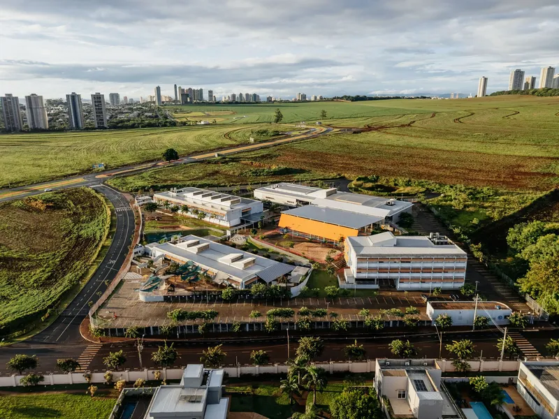 Aerial view of the campus complex with white roofs and orange canopy surrounded by farmland