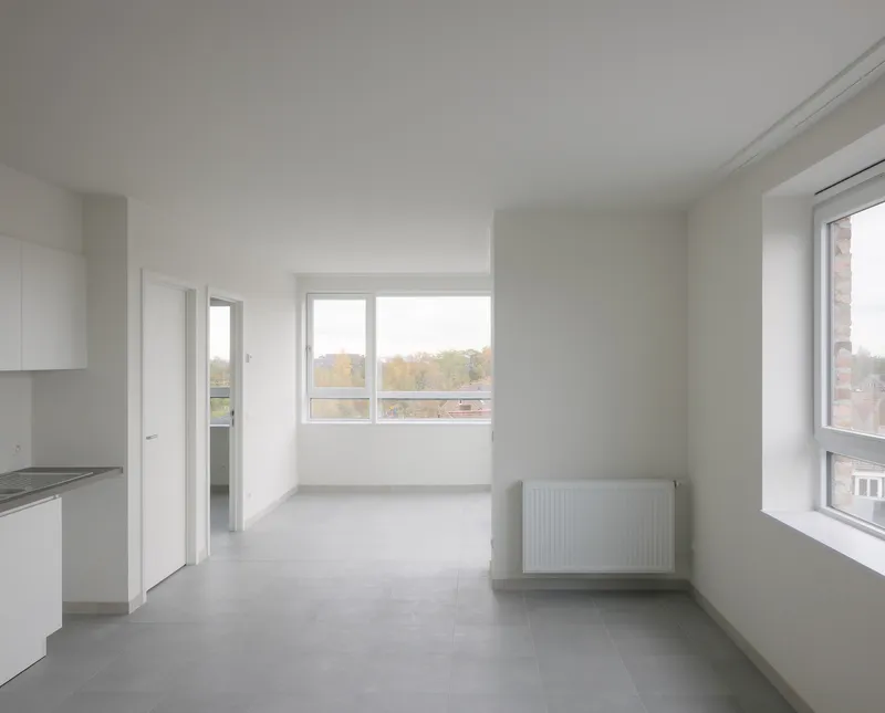 White interior room with grey tile floor and windows overlooking autumn foliage