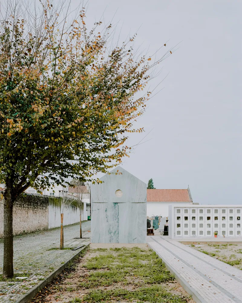 View past autumn foliage of the chapel volume adjacent to a perforated screen wall