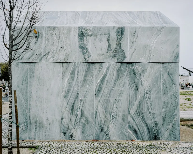 Rear elevation of the marble-clad chapel volume showing horizontal panel joints in the cemetery