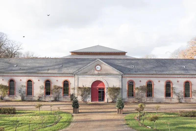 Symmetrical facade of the restored building with arched windows and new tiered roof visible behind under cloudy sky