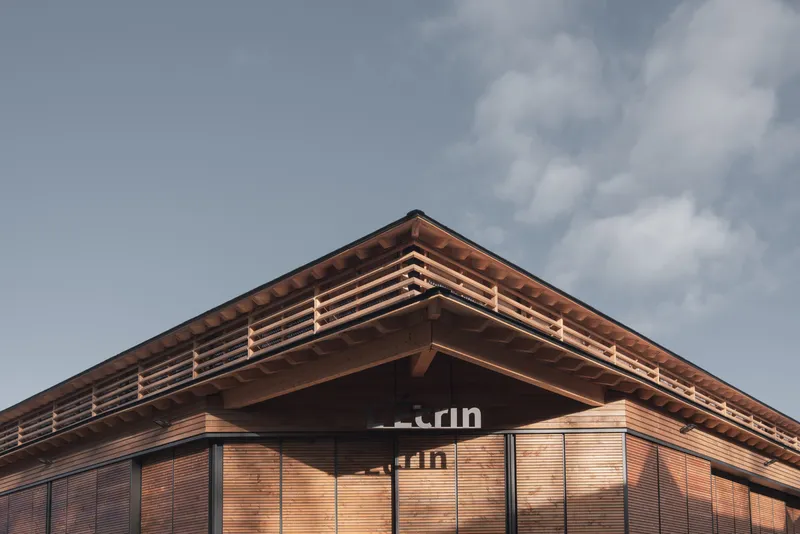 Upward view of the timber louvered roofline with horizontal slats under a cloudy sky