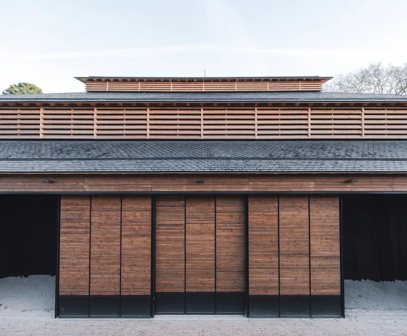 Facade with horizontal timber louvered screens above vertical slatted panels and dark tiled roof
