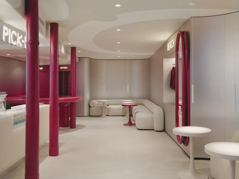 Retail interior with burgundy steel columns, cream sectional seating and curved ceiling cutouts with recessed lighting