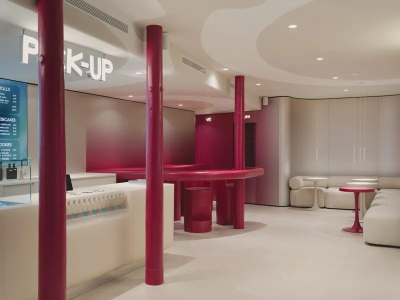 View across the space showing burgundy circular counter with columns and illuminated pickup signage