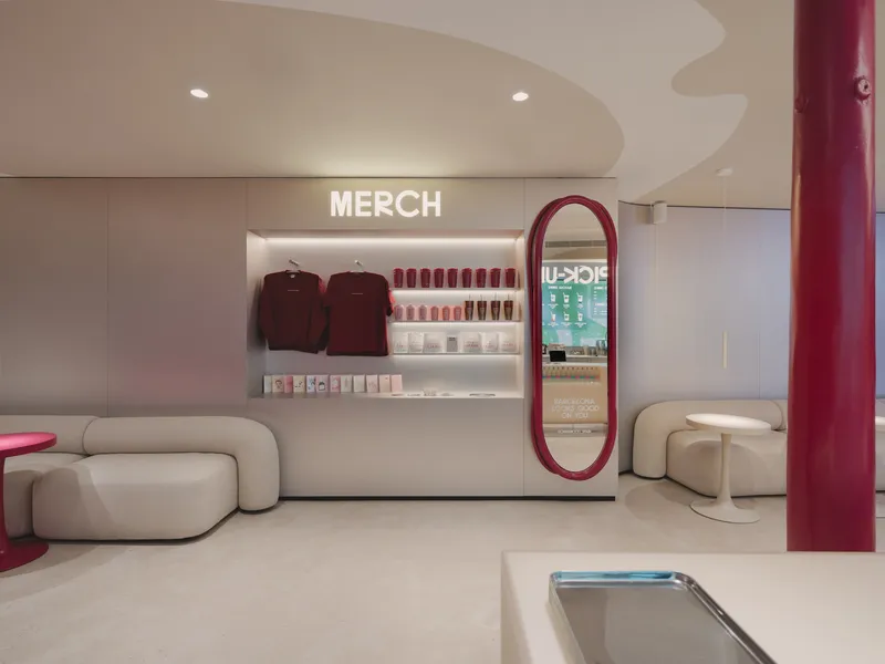 Merchandise wall with backlit shelving, oval mirror kiosk and curved soffit under recessed ceiling
