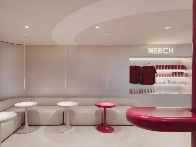 Interior seating area with curved banquette, white side tables, and illuminated merchandise alcove beyond