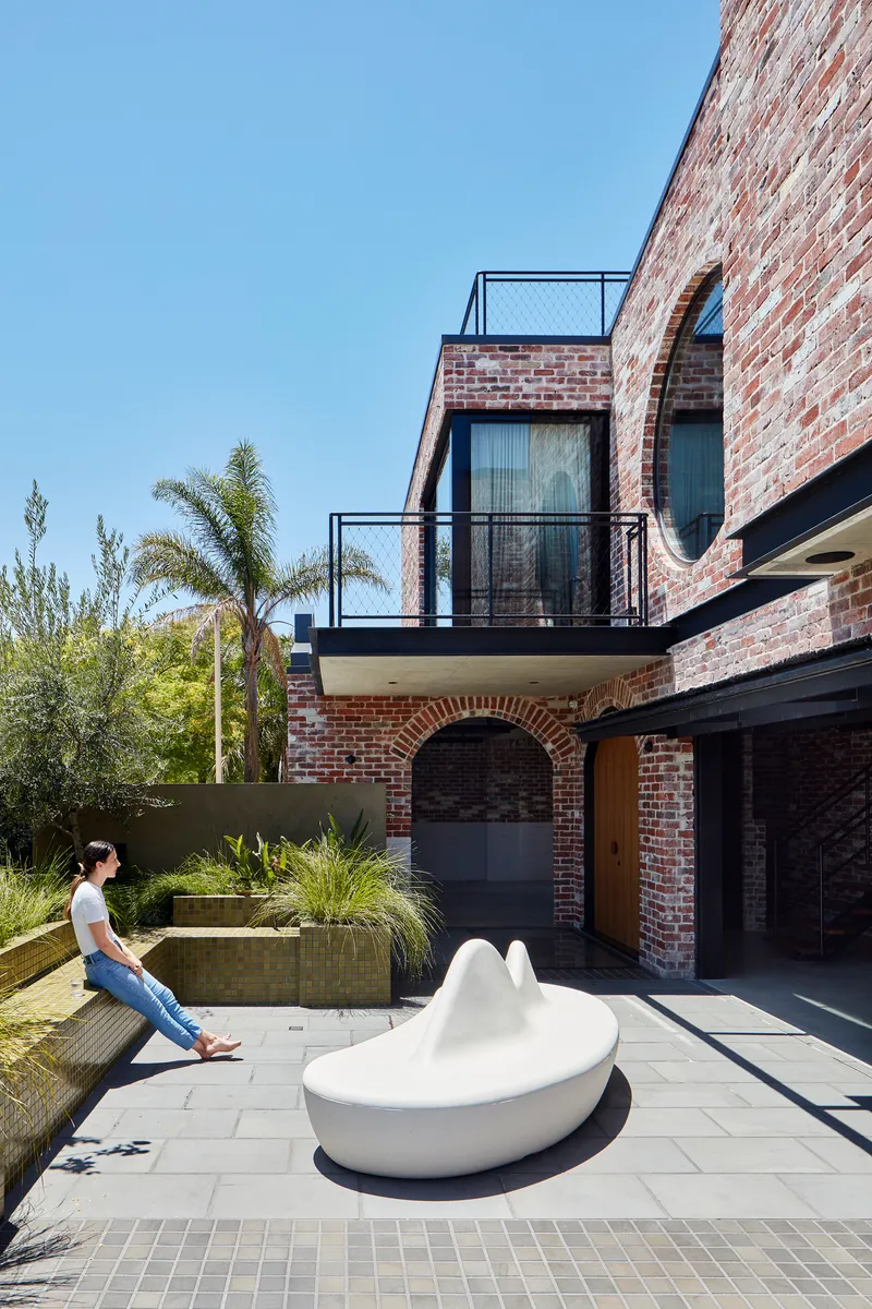 Courtyard with white sculptural seating and a woman sitting on the concrete planter edge