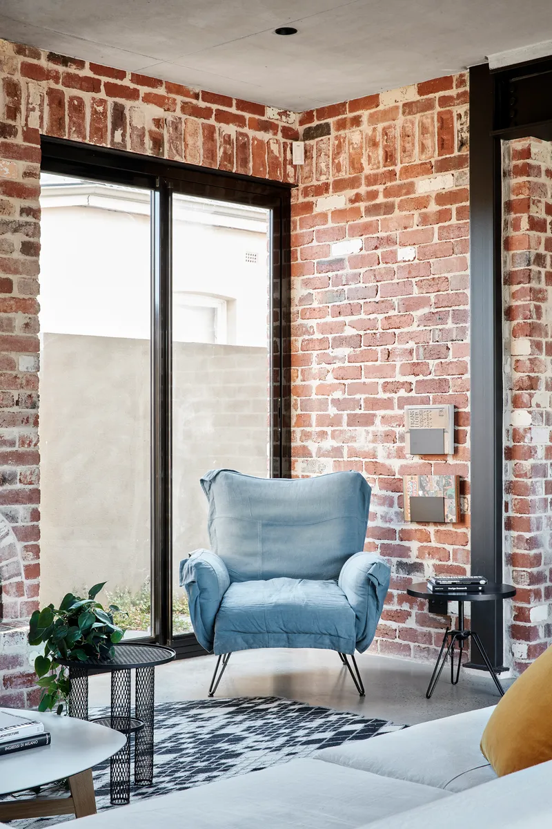 Corner seating area with exposed brick walls and black-framed glazing overlooking a courtyard