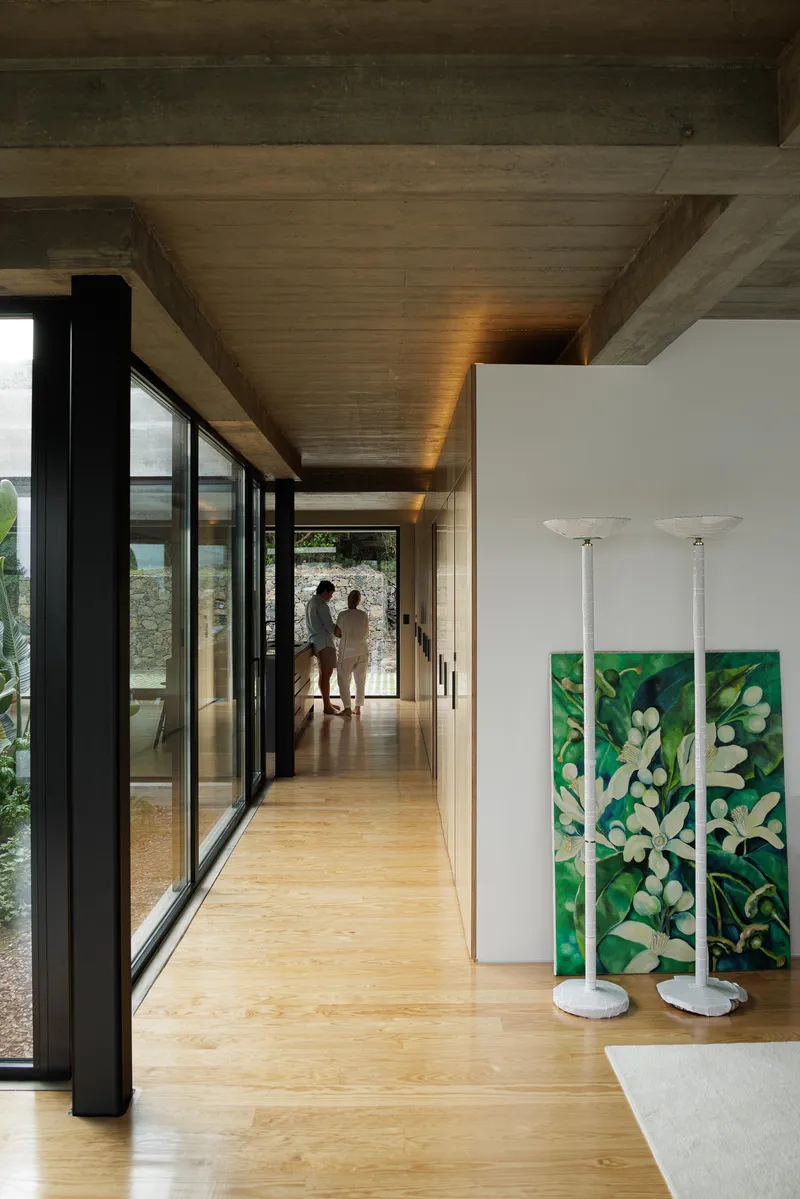 Corridor view with two figures silhouetted in backlit passage beneath timber-clad ceiling soffit