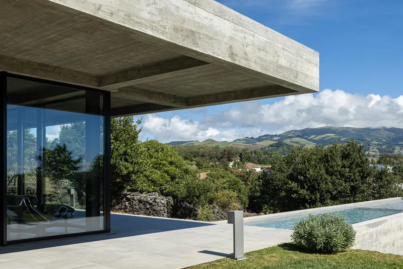 Infinity pool terrace under the cantilevered concrete slab framing distant mountain views
