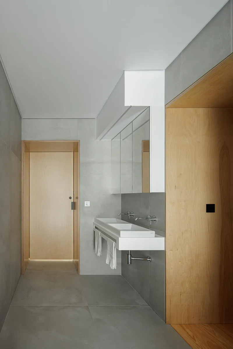 Bathroom interior with concrete walls, skylight above and timber door threshold to bedroom