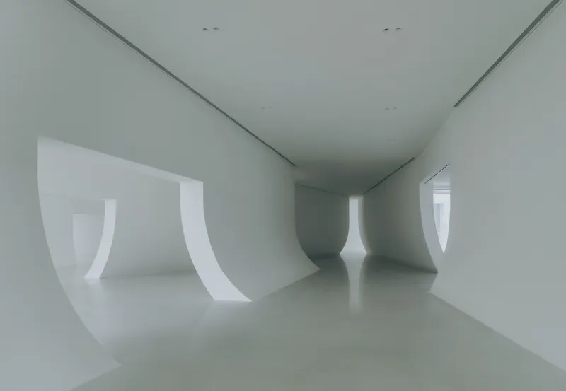 Interior gallery with curved white walls and window openings creating continuous spatial flow
