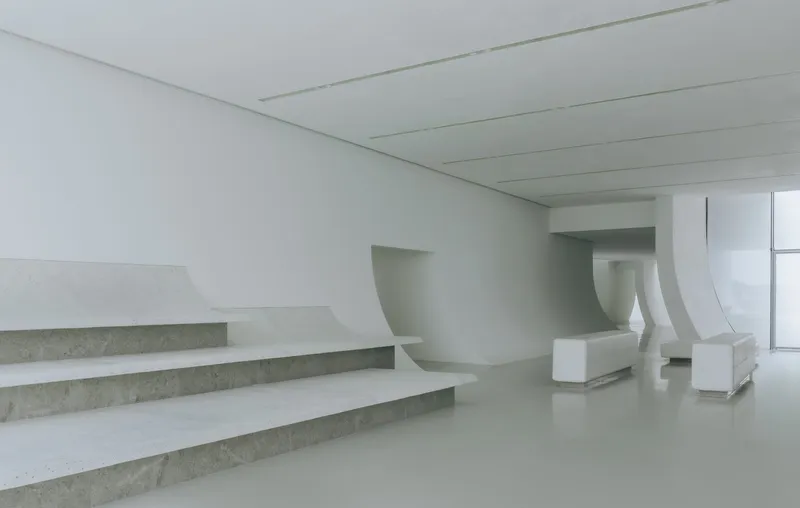 Interior view of the broad staircase with exposed concrete treads and curved white balustrades