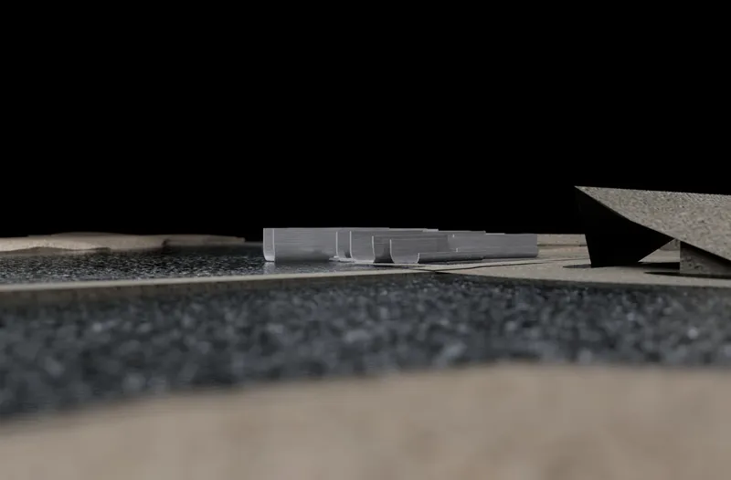 Eye-level view of a physical model showing a low horizontal volume between textured landscape planes
