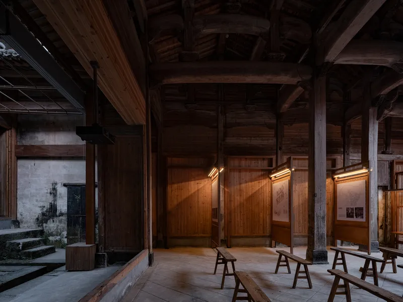 Gallery space with angled illuminated display panels mounted on timber walls and wooden benches below