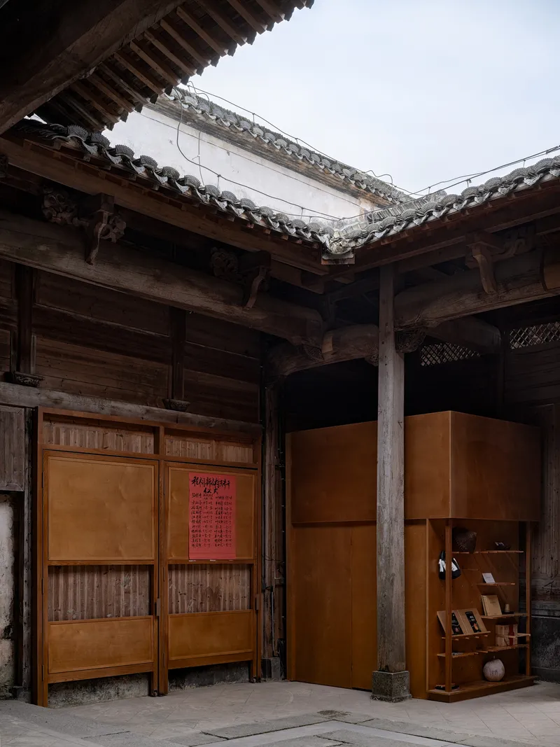 Courtyard view with amber exhibition panels set within exposed timber frame structure under traditional tiled roofs