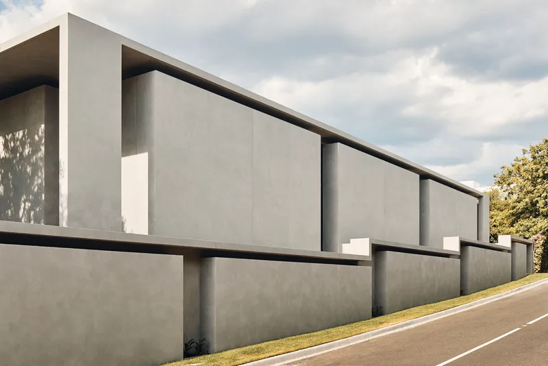 Long concrete facade with vertical recesses and narrow windows set between smooth panel surfaces
