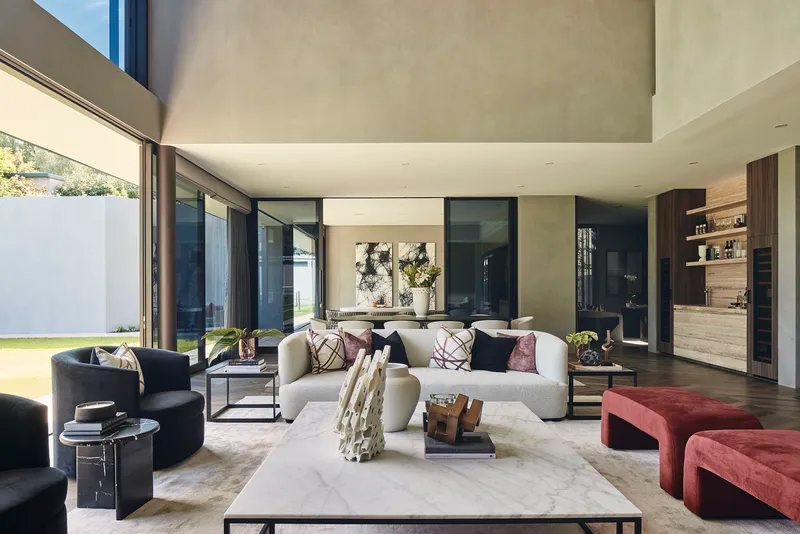 Open-plan living space with concrete ceiling planes and floor-to-ceiling glazing overlooking a courtyard