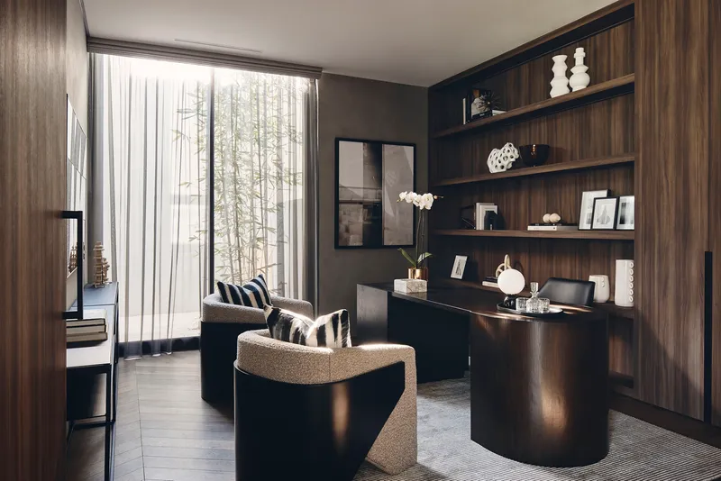 Study nook with dark timber shelving and desk beneath a window with sheer curtains