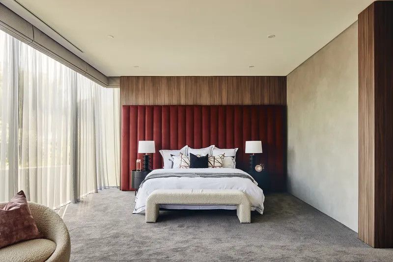 Bedroom with maroon channel-tufted headboard and floor-to-ceiling curtains