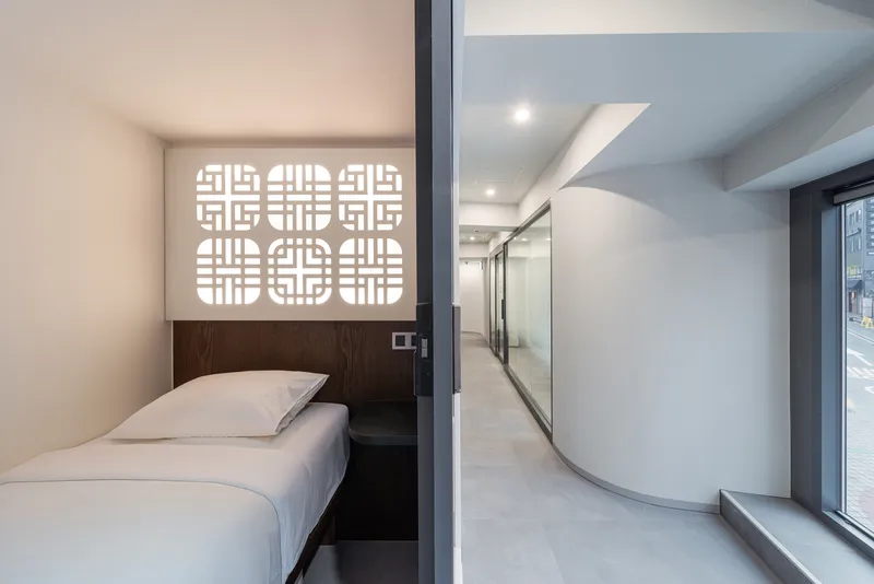 View from bedroom through glass corridor wall showing curved partition and window beyond