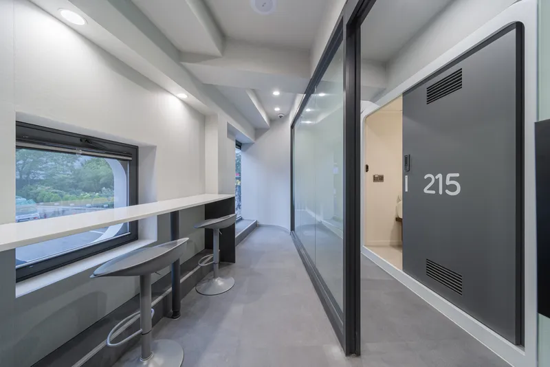 Corridor with built-in seating alcove, numbered door and glass partition at dusk