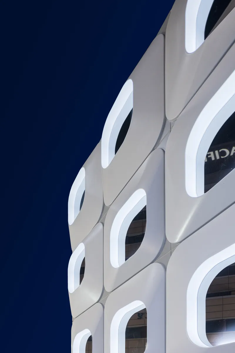 Upward view of the rounded square window openings against a deep blue evening sky