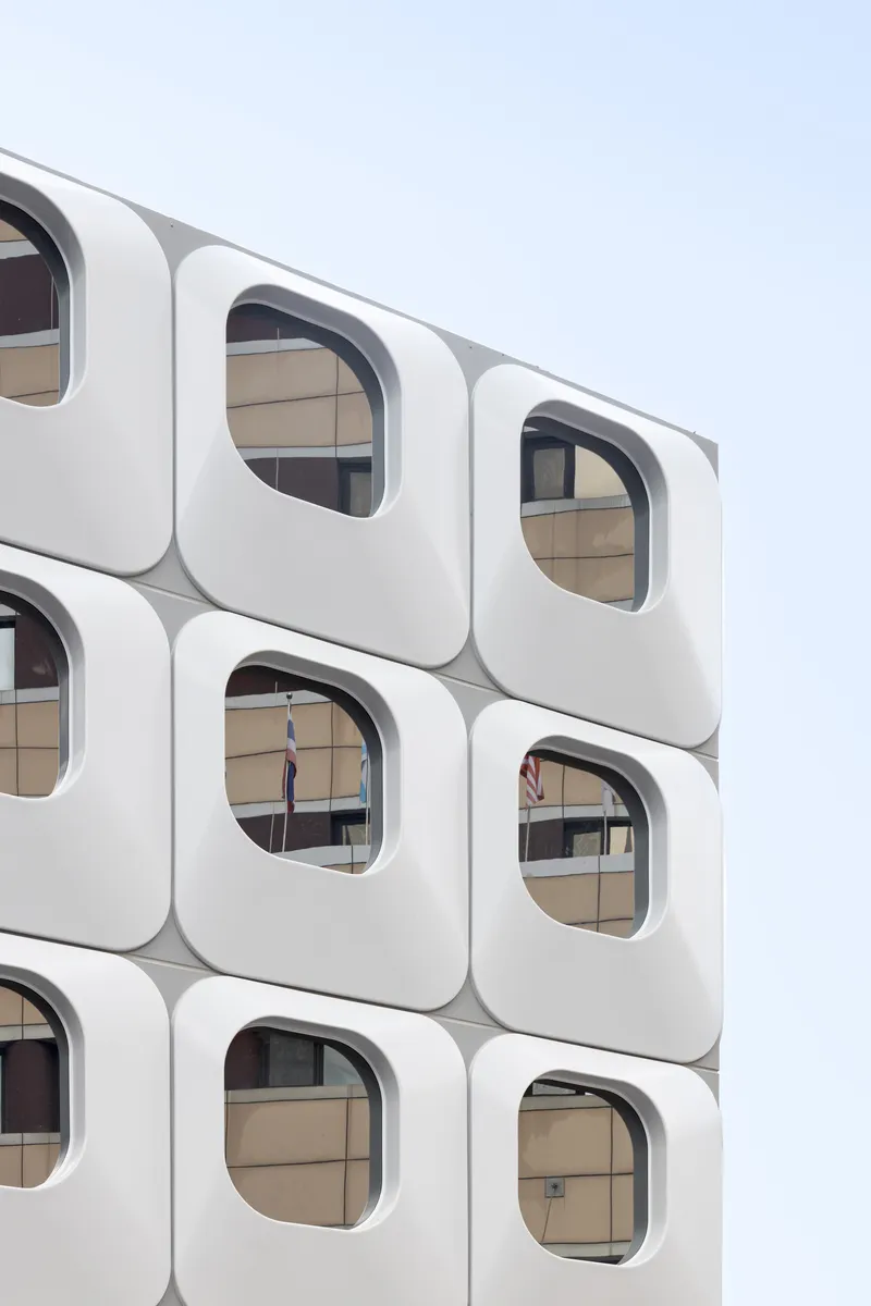 Close-up of white rounded-square window modules revealing interior office spaces through the glazing