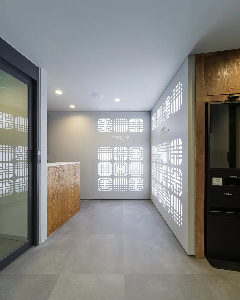 Interior corridor with perforated white wall panel, polished concrete floor and recessed ceiling lights