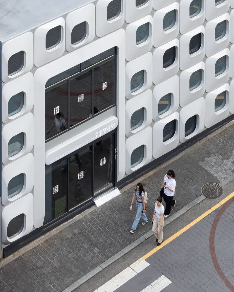 Elevated view of the entrance canopy and three pedestrians walking along the sidewalk below