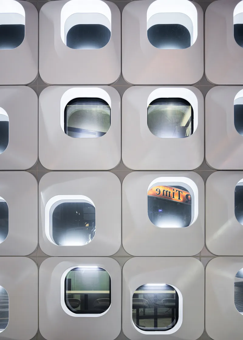 Close-up of the white facade panels showing the depth of the rounded window frames