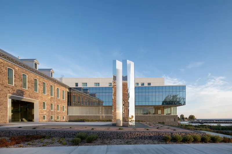 View across the planted courtyard showing the historic brick building alongside the glass and panel addition