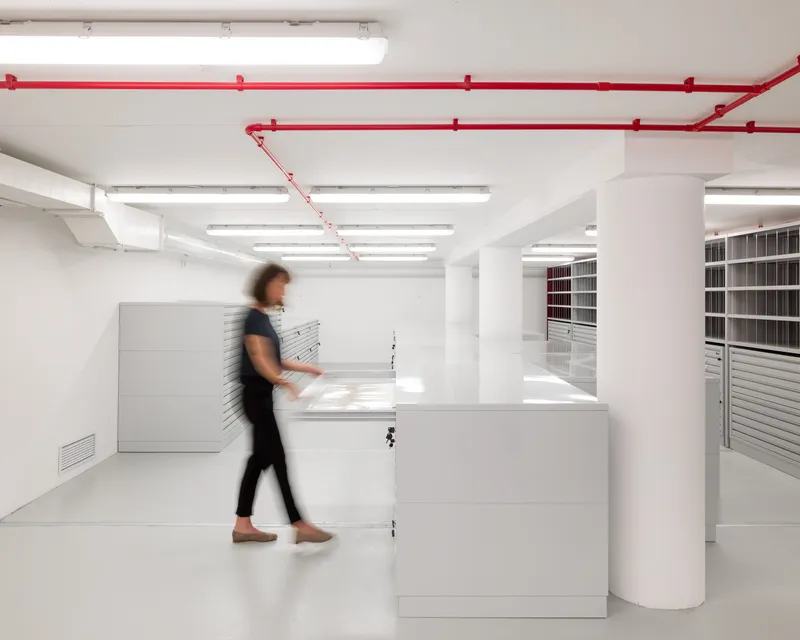 White reception desk with blurred figure walking past red exposed conduit on ceiling
