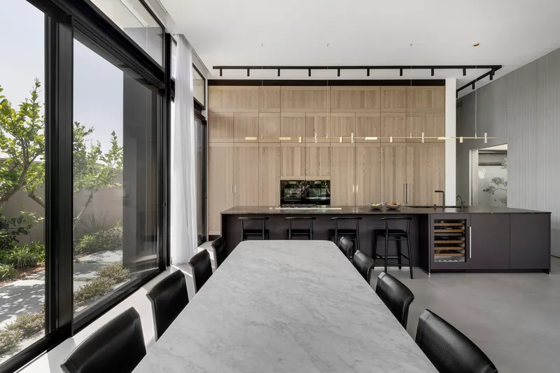 Open kitchen and dining area with floor-to-ceiling glazing overlooking a planted courtyard