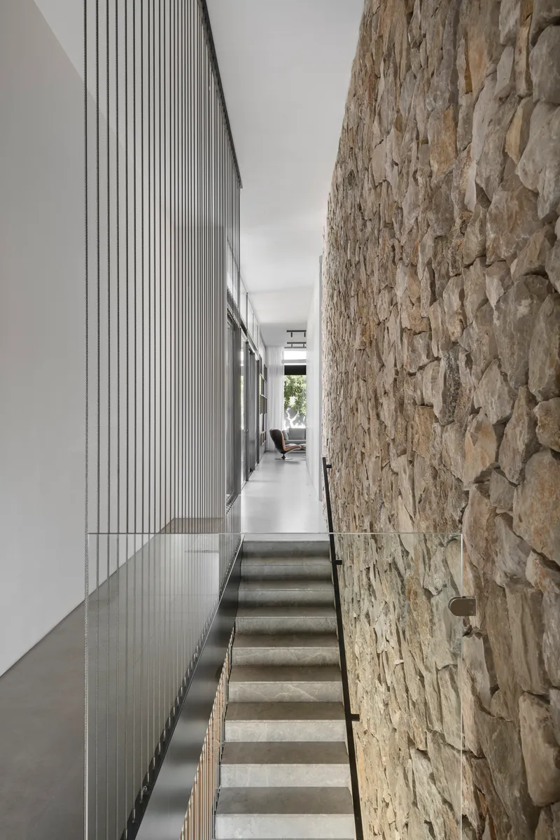 Concrete stairs flanked by a rough stone wall and vertical timber battens in natural light