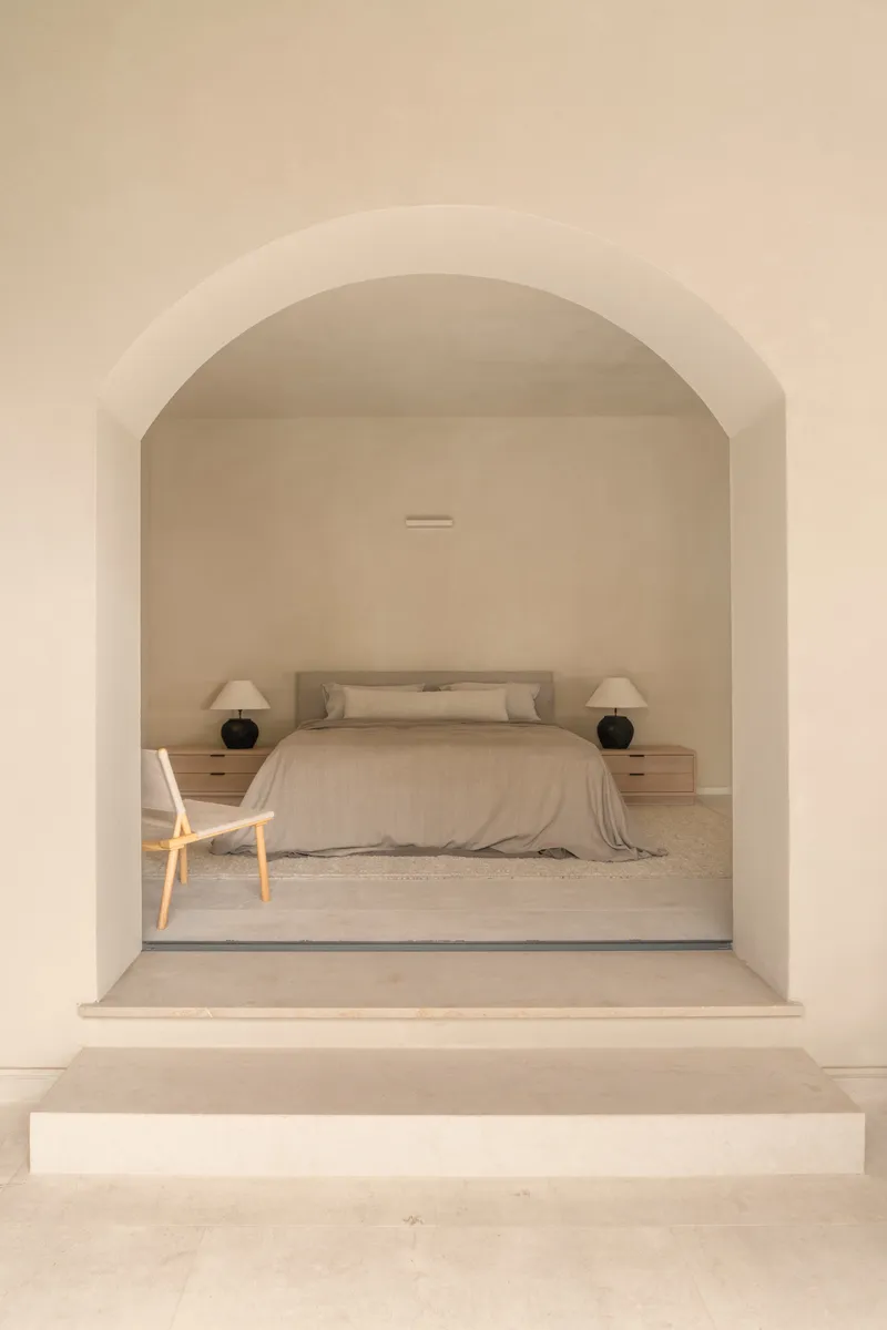 Arched doorway framing a bedroom with stepped threshold and pale stone floor