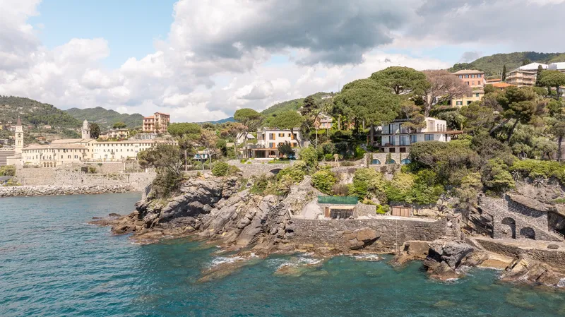 Aerial view of the rocky promontory jutting into the turquoise water with hillside village behind