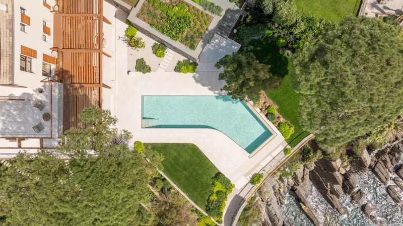 Aerial view of the angled pool deck and lawn bordered by rocky coastline