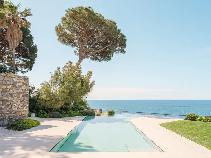 Rectangular pool channel set into pale paving with garden and sea horizon beyond