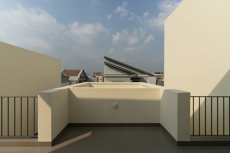 Rooftop terrace with cream-colored parapet walls and metal railing under an afternoon sky