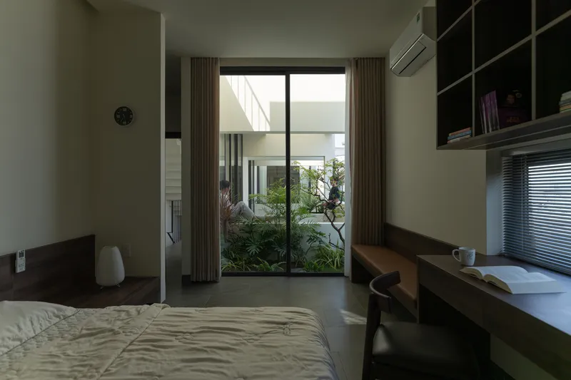 Bedroom with timber desk and glass doors opening to a small planted courtyard