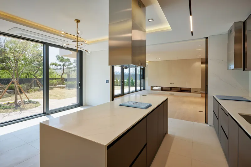 Open kitchen with island, recessed cove lighting, and sliding glass doors to a garden terrace