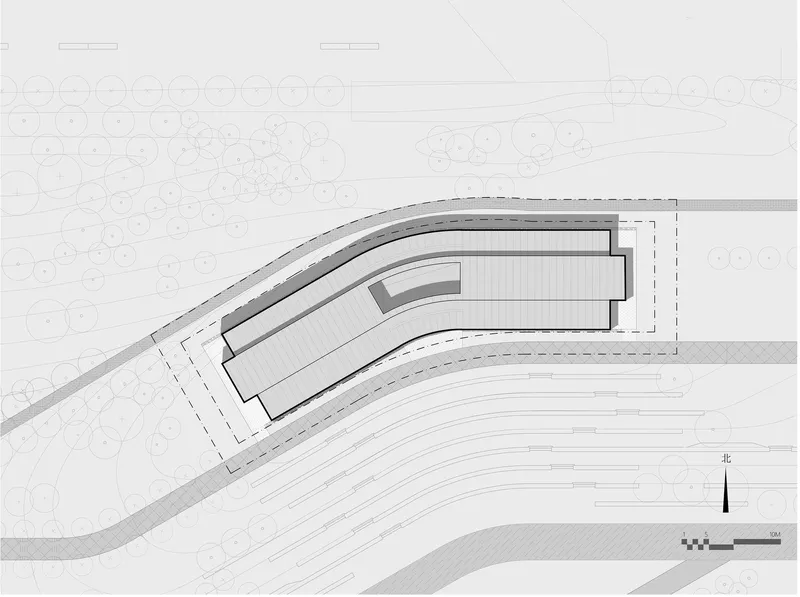 Site plan drawing showing a curved building footprint bordered by trees and roadways