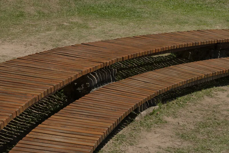Timber slat benches revealing the shadow-striped gap between parallel deck sections