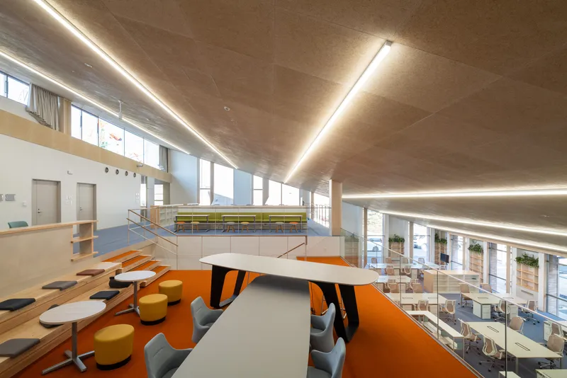 Mezzanine seating area with orange carpet, tiered benches, and views down to workspaces below