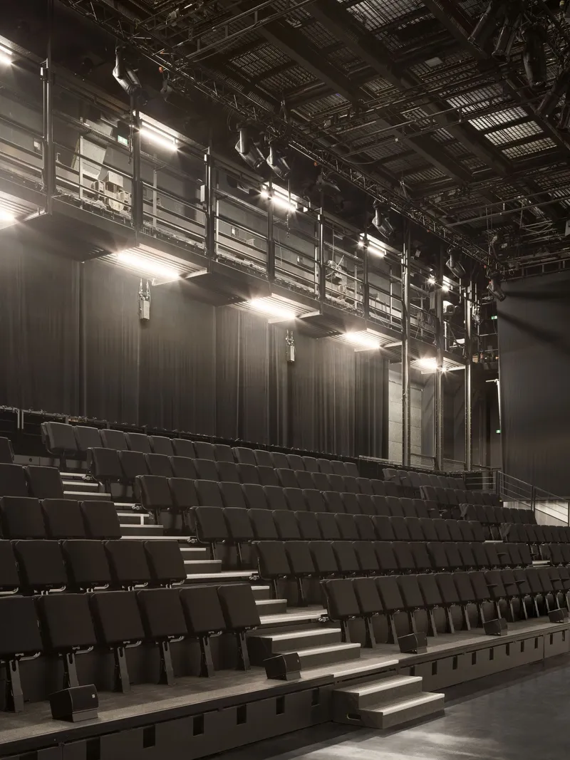 Angled view of the raked seating rows with stage curtains and suspended lighting infrastructure