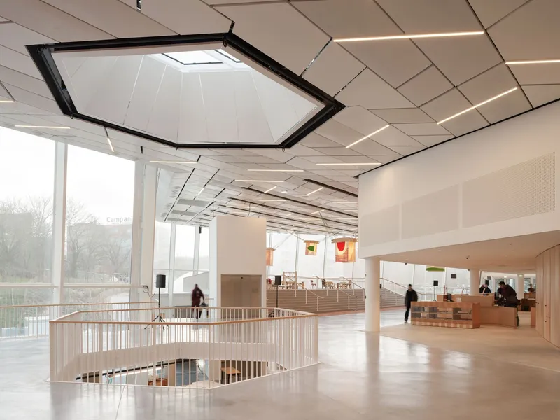 Interior gallery space with geometric ceiling panels, hexagonal skylight and curved stairwell opening