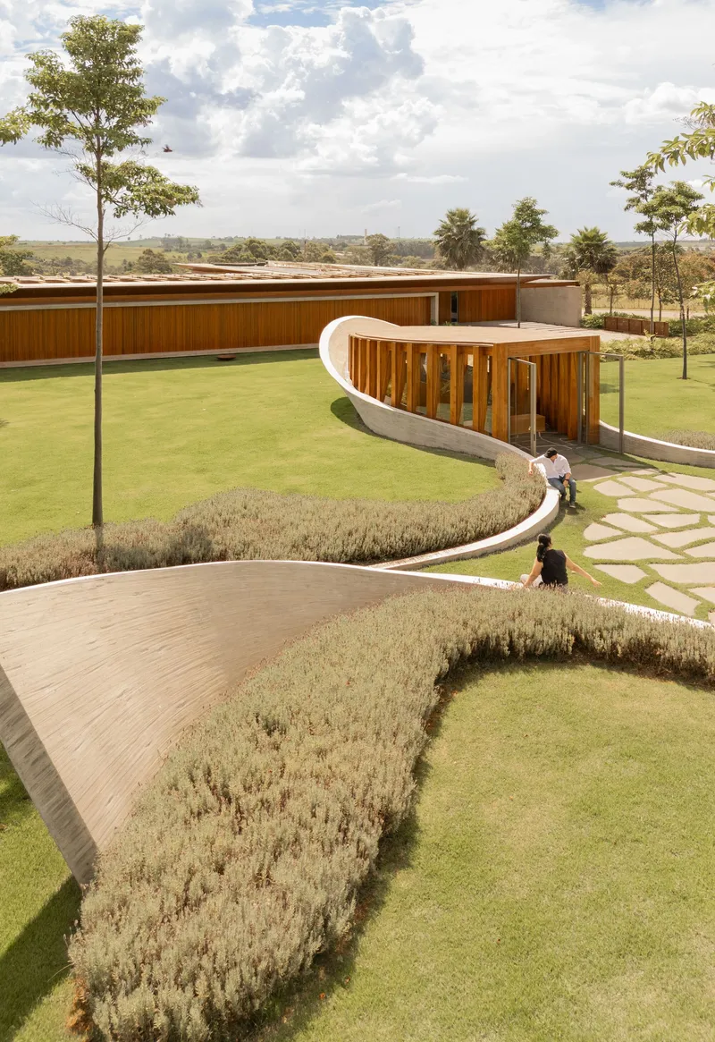 Winding stone pathways through planted beds with curved white pavilion and two figures in the landscape