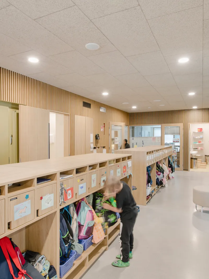 Hallway with timber cubby storage for coats and backpacks as a child retrieves belongings